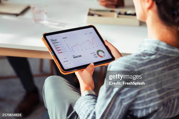 imprenditrice che analizza i rapporti finanziari su tablet digitale - inquadratura da sopra le spalle foto e immagini stock