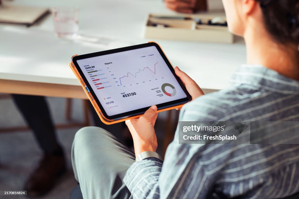 Businesswoman Analyzing Financial Reports on Digital Tablet