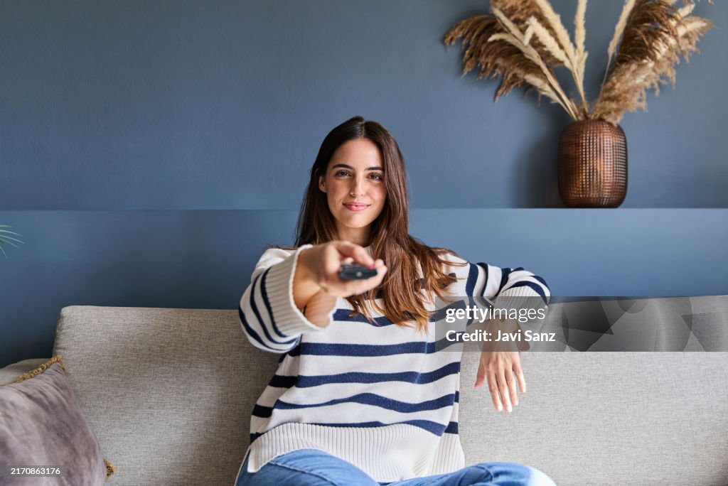 Woman In Control Beautiful Woman Sitting On A Sofa In Her Modern Living Room Holding A ...