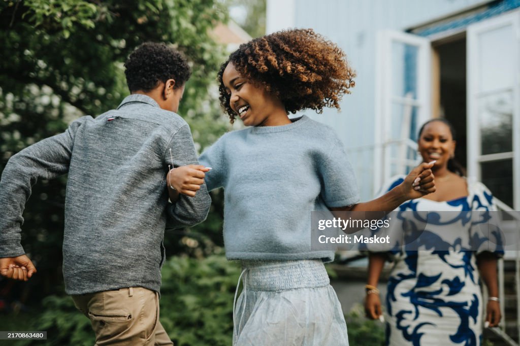 Carefree sister dancing arm in arm with brother during garden party