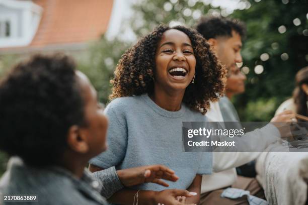 portrait of cheerful curly hair girl having fun with brother during social gathering in back yard - sisters playing stock pictures, royalty-free photos & images