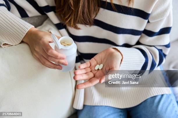 unkenntliche frau, die pillen aus einer flasche gießt und sich um ihre gesundheit kümmert. moment der selbstfürsorge für die behandlung einer krankheit - nahrungsergänzungsmittel stock-fotos und bilder