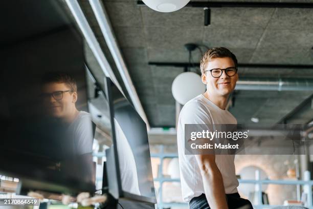 portrait of smiling young computer programmer at tech startup office - europese etniciteit stockfoto's en -beelden