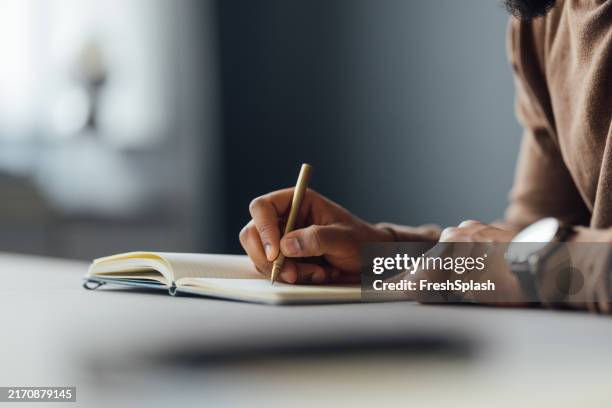 gros plan d’un homme écrivant dans un cahier sur un bureau - écrivain photos et images de collection