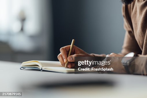 Close-up of Man Writing in a Notebook at a Desk Close-up of Man Writing in a Notebook at a Desk