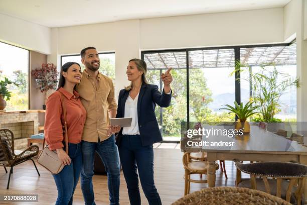 real estate agent showing a house for sale to a couple - real estate agent stock pictures, royalty-free photos & images