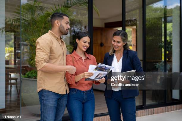 pareja hablando con un agente de bienes raíces mientras mira una casa - agente inmobiliario fotografías e imágenes de stock