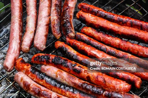 Sausages, including Merguez and Chipolata, are arranged on a barbecue grill in a private garden in Saint Romain de Popey in the Auvergne Rhone Alpes...