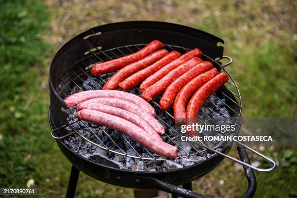 Sausages, including Merguez and Chipolata, are arranged on a barbecue grill in a private garden in Saint Romain de Popey in the Auvergne Rhone Alpes...