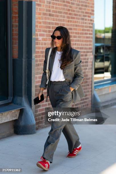 Guest is seen wearing a grey blazer, white top, grey pant, red shoes, black sunglasses and cream bag outside the Ulla Johnson show during New York...
