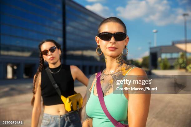 two young woman standing looking at camera - attitude stock pictures, royalty-free photos & images