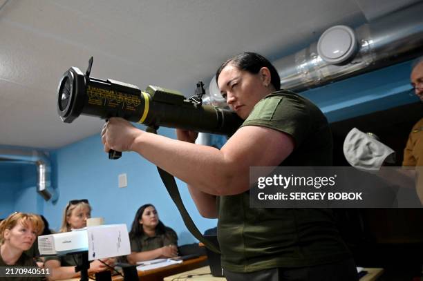 Civilian woman holds an anti-tank grenade launcher as she takes part in a military training given by former Ukrainian servicemen at a civic centre at...