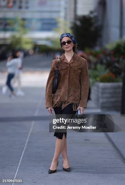 Guest seen wearing a blue pattern bandana headband, gold round earrings, DMY Studios black oval sunglasses, vintage brown suede leather jacket with...