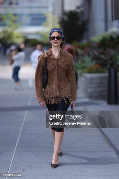 Guest seen wearing a blue pattern bandana headband, gold round earrings, DMY Studios black oval sunglasses, vintage brown suede leather jacket with...