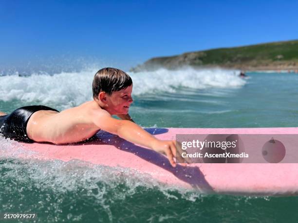young boy surfs wave in ocean - sennen stock pictures, royalty-free photos & images