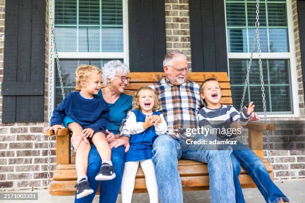 abuelos riendo y jugando en un columpio de porche en el campo - medicare fotografías e imágenes de stock
