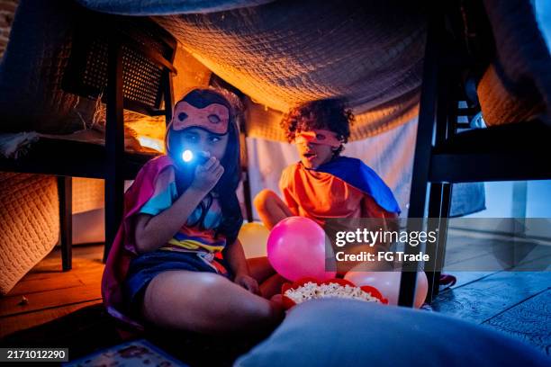 siblings playing as heroes in a tent at home - childrens day stock pictures, royalty-free photos & images
