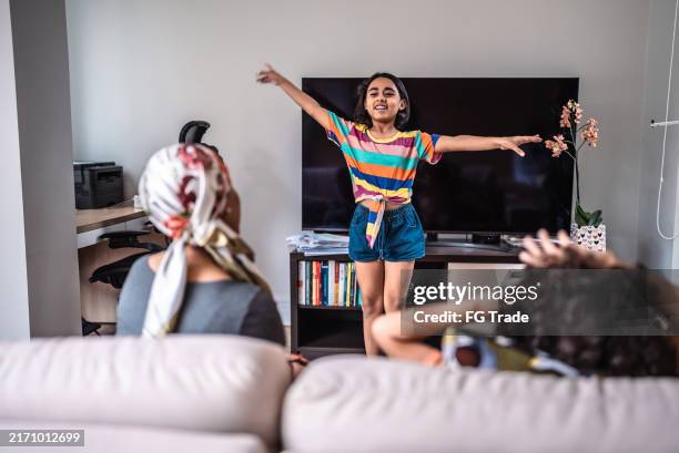 girl playing charades with family at home - pantomime stock pictures, royalty-free photos & images