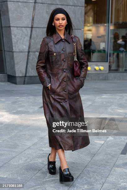 Guest is seen wearing a brown printed coat, black shoes, black headband and carrying a maroon bag outside the Coach show during New York Fashion Week...