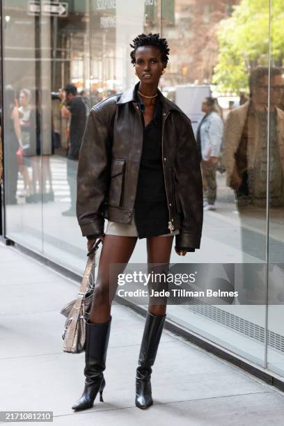Model is seen wearing a brown jacket, black top, grey shorts, black boots and carrying a silver bag outside the Carolina Herrera show during New York...