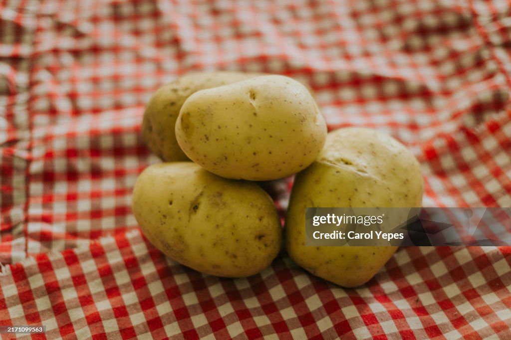 Raw potatoes in red checkered tablecloth