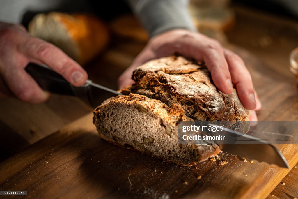 Man cutting bread on chopping board