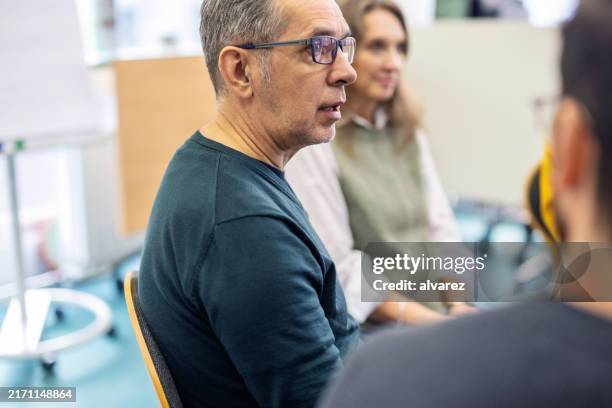 senior counselor talking to participants in support group meeting at a community center - guidance stock pictures, royalty-free photos & images