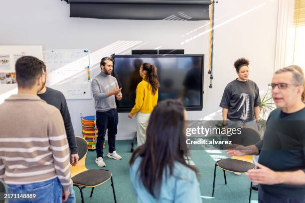 einzelpersonen stehen in zweierteams und sprechen während des beratungsgesprächs miteinander - sich verschönern stock-fotos und bilder
