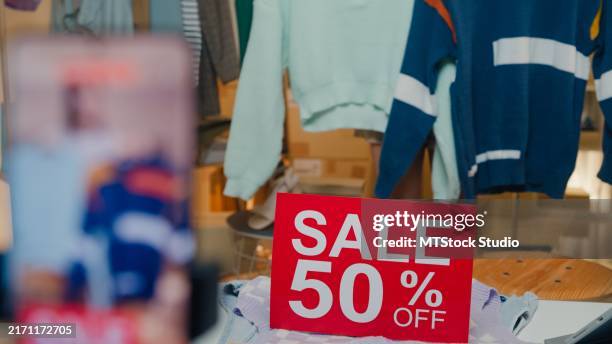 closeup of young asian woman live streaming on phone show new collection fashion clothes to customer in shop at night. sme small business e-commerce. - sales promoter stock pictures, royalty-free photos & images