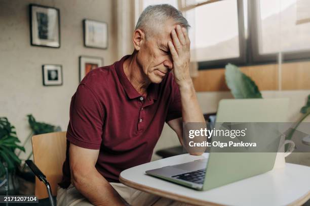 tired mature man uses laptop - com as mãos na cabeça imagens e fotografias de stock
