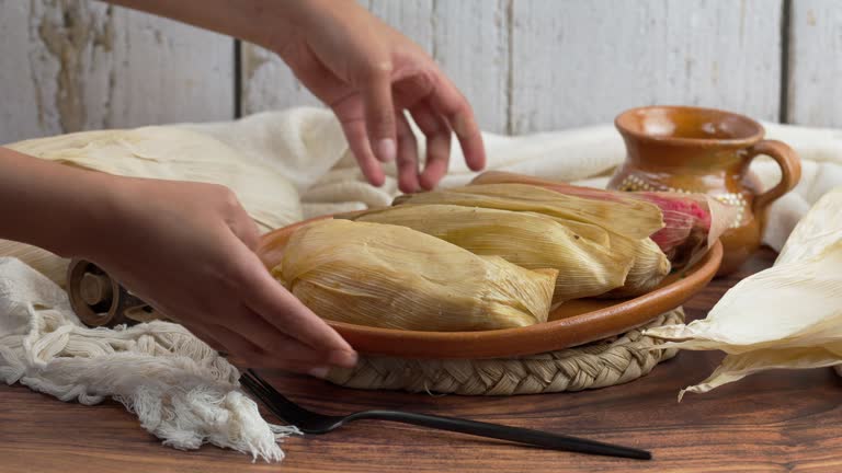 https://media.gettyimages.com/id/2171209920/video/latin-woman-places-a-traditional-clay-plate-on-the-table-with-tamales-of-different-flavors.jpg?b=1&s=640x640&k=20&c=fFOHrI_NQfnYpLGs94-FP1FlwLJk0KyrzruibIuwuBQ=