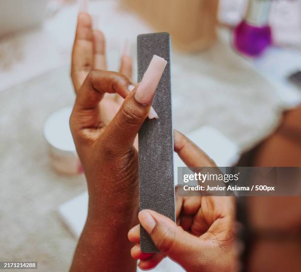 young woman as a nail tech working on custom stick-on nails for client - nail file stock pictures, royalty-free photos & images