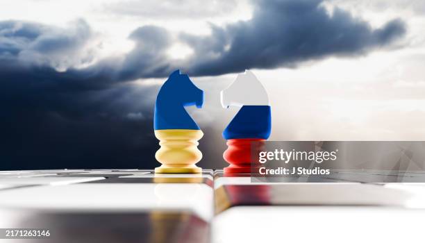 face off of two rooks in ukraine and russian flag colors with moody sky - russische-invasion-in-die-ukraine stock-fotos und bilder
