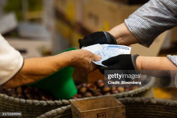 Customer pays his purchase with South Korean 1,000 won banknotes at the Cheongyangni Market in Seoul, South Korea, on Friday, Sept. 13, 2024. South...