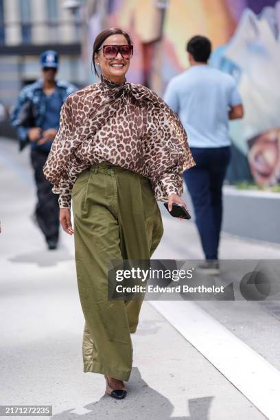 Guest wears dark brown sunglasses, dark brown leopard animal pattern/print long sleeve flowy shirt, dark green high waisted loose pants, beige and...
