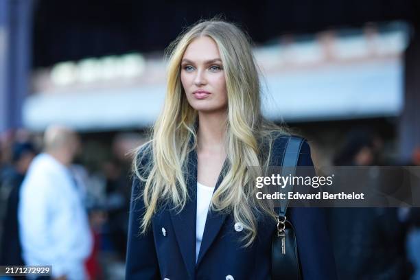 Romee Strijd wears navy blue oversized blazer jacket, white tank top, navy blue shorts, shiny black leather bag, outside Tommy Hilfiger, during the...