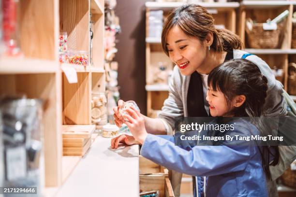 young asian mother and daughter shopping for souvenirs while travelling in a new city - gift shop stock pictures, royalty-free photos & images