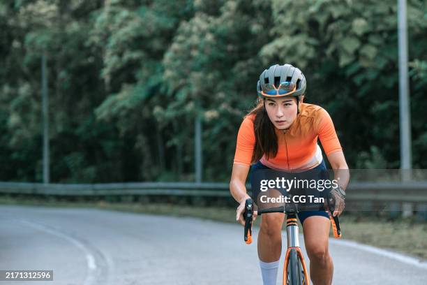 asian chinese athletic woman cycling . sporty fit female riding road bike on road exercise. endurance and cardio during a workout and training - road cycling stock pictures, royalty-free photos & images