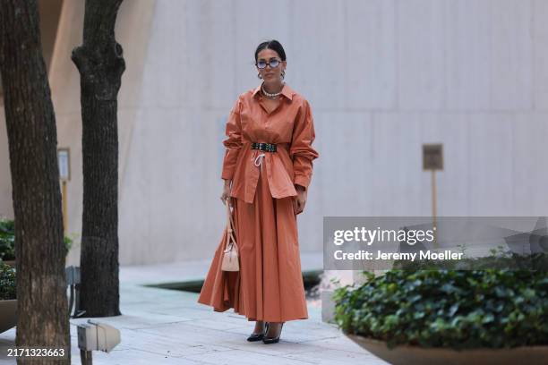 Olga Sokolenko seen wearing Miu Miu brown sunglasses with blue tinted lenses, silver hoop earrings, silver necklace, pearl necklace, Rogov orange...