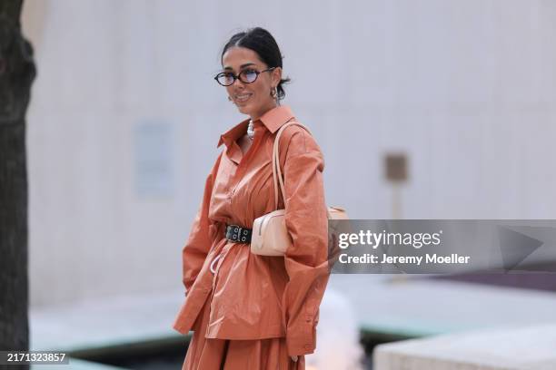 Olga Sokolenko seen wearing Miu Miu brown sunglasses with blue tinted lenses, silver hoop earrings, silver necklace, pearl necklace, Rogov orange...