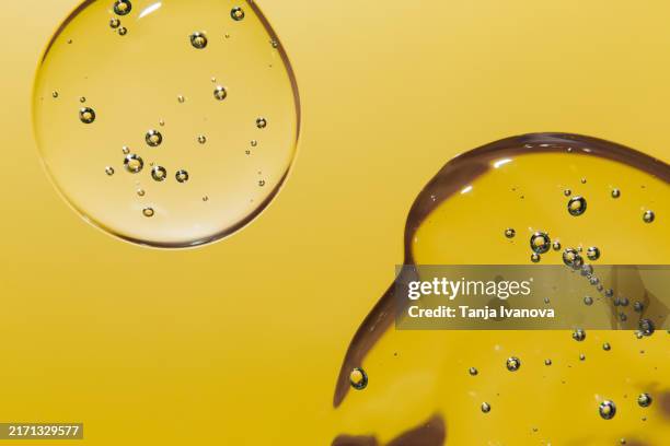 texture of transparent drops gel or serum cosmetic with bubbles on yellow background. liquid hyaluronic acid gel. - peptide stock pictures, royalty-free photos & images