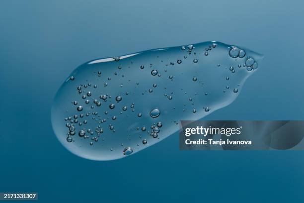 smear of transparent gel on blue background. - haargel stock-fotos und bilder