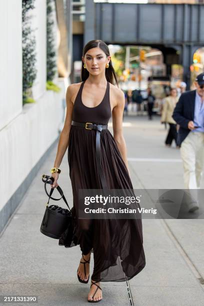 Kate Bartlett wears brown fringed belted dress, bucket bag outside Michael Kors during New York Fashion Week on September 10, 2024 in New York City.
