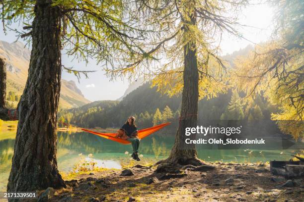 gelassene frau, die sich im herbst in einer hängematte am schweizer see ausruht - hängematte stock-fotos und bilder