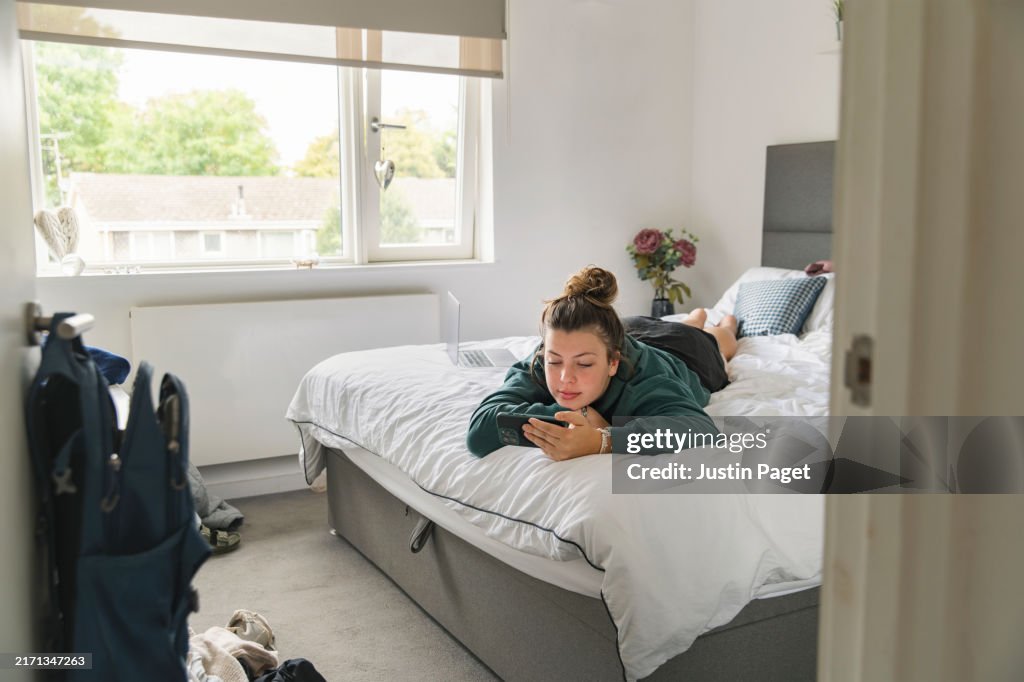 WS of a young woman lying in bed on her smart phone - bed rotting