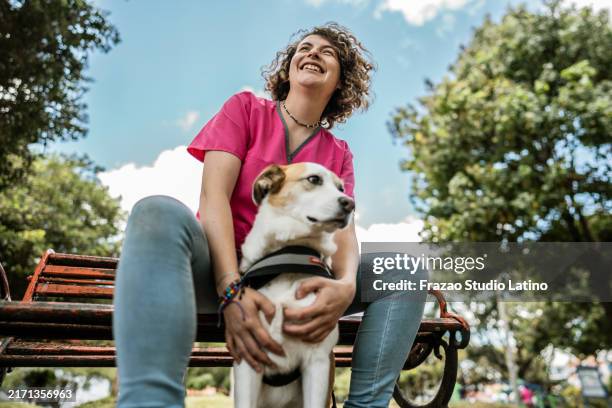 female animal trainer caressing dog in a public park - service animals stock pictures, royalty-free photos & images
