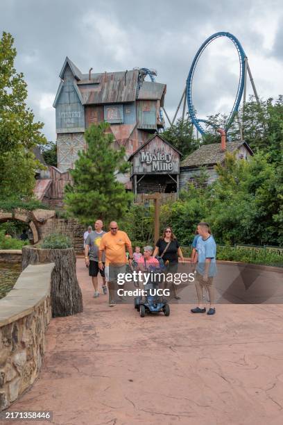 Family of park guests walking past the Mystery Mine roller coaster ride at the Dollywood amusement park in Pigeon Forge, TN.