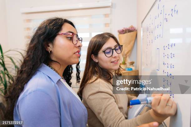 two female university students studying math in front of a whiteboard, preparing for their exam at home - math homework stock pictures, royalty-free photos & images