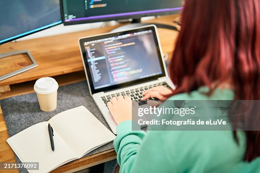 Computer programmer writing code on laptop in office Computer programmer writing code on laptop in office