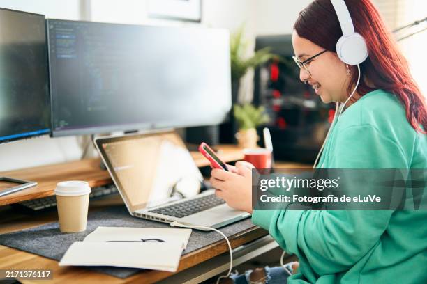 female computer programmer using smartphone and working from home office - web programmer stock pictures, royalty-free photos & images